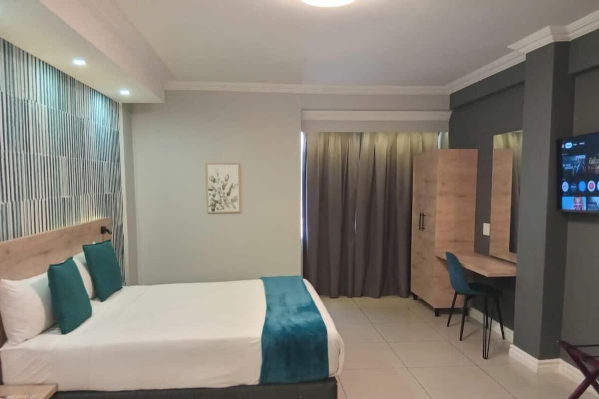 Een hotelkamer met een bed, een bureau, een stoel, een televisie en een gordijn.