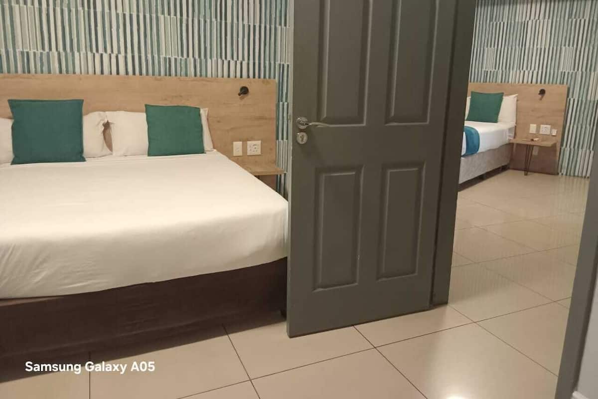 Een hotelkamer met een bed, nachtkastje en een deur.
