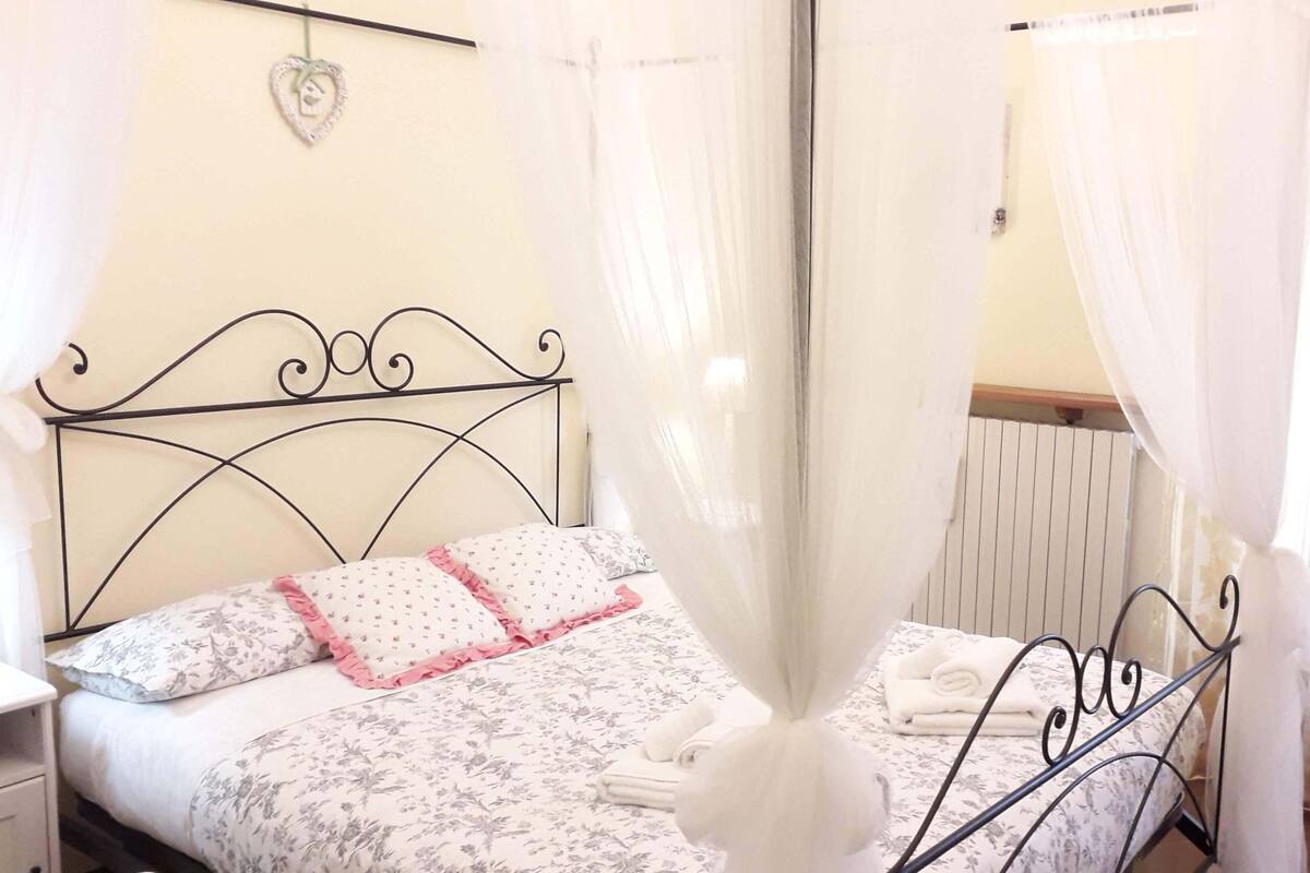 Un dormitorio con cama, cortinas y radiador.