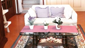 A room with a white sofa, a glass coffee table, and a staircase with a white curtain. - B&B Le Mi' Cocche (Capannori)
