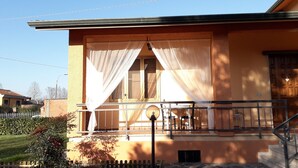 A two-story building with a balcony, a wooden door, and a window with curtains. - B&B Le Mi' Cocche (Capannori)