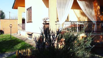 Ein Haus mit Balkon, einem kleinen Garten und einer Ziegelmauer im Hintergrund.