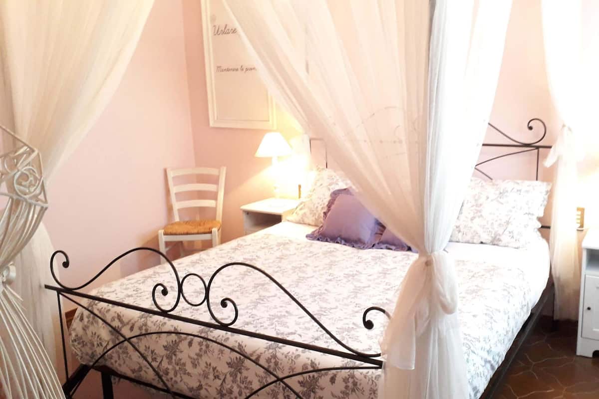 Un dormitorio con cama, una silla, una mesita de noche y un cartel en la pared.
