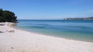 A beach with clear water, a sandy shore, and a distant town. - Apartamento Umag Valica, near the beach with swimming pool, 2 bedrooms, barbecue (Valizza)