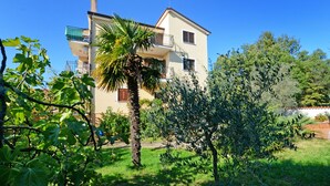 A two-story building with a balcony, surrounded by greenery and trees. - Apartamento Umag Valica, near the beach with swimming pool, 2 bedrooms, barbecue (Valizza)