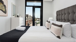 A modern hotel room with a large bed, a black headboard, and a view of the city through a large window. - The Signature 401 (Cape Town)
