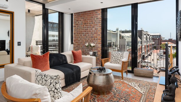 A modern living room with a large window, a brick wall, and a view of the city. - The Signature 401 (Cape Town)