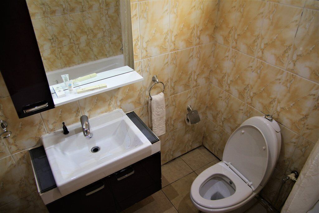 Un baño con lavabo, espejo, inodoro y toallero.