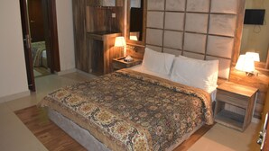 A bedroom with a large bed, wooden headboard, bedside tables, a mirror, and a wardrobe. - Hotel Akkas (Murree)