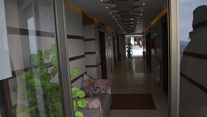 A hallway with a sofa, a plant, and a fire extinguisher. - Hotel Akkas (Murree)