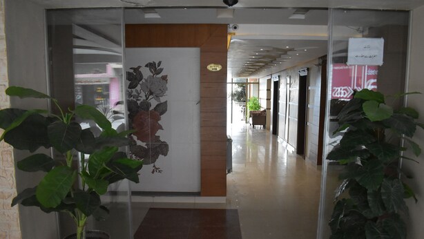 A hotel lobby with a modern design, featuring a reception desk, a large floral mural, and potted plants. - Hotel Akkas (Murree)