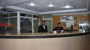 A hotel reception desk with a clock, calendar, and a sign indicating check-out time. - Hotel Faran Murree (Murree)
