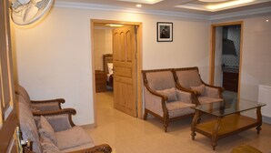 A living room with two sofas, a glass coffee table, and a wooden door leading to another room. - Hotel Faran Murree (Murree)