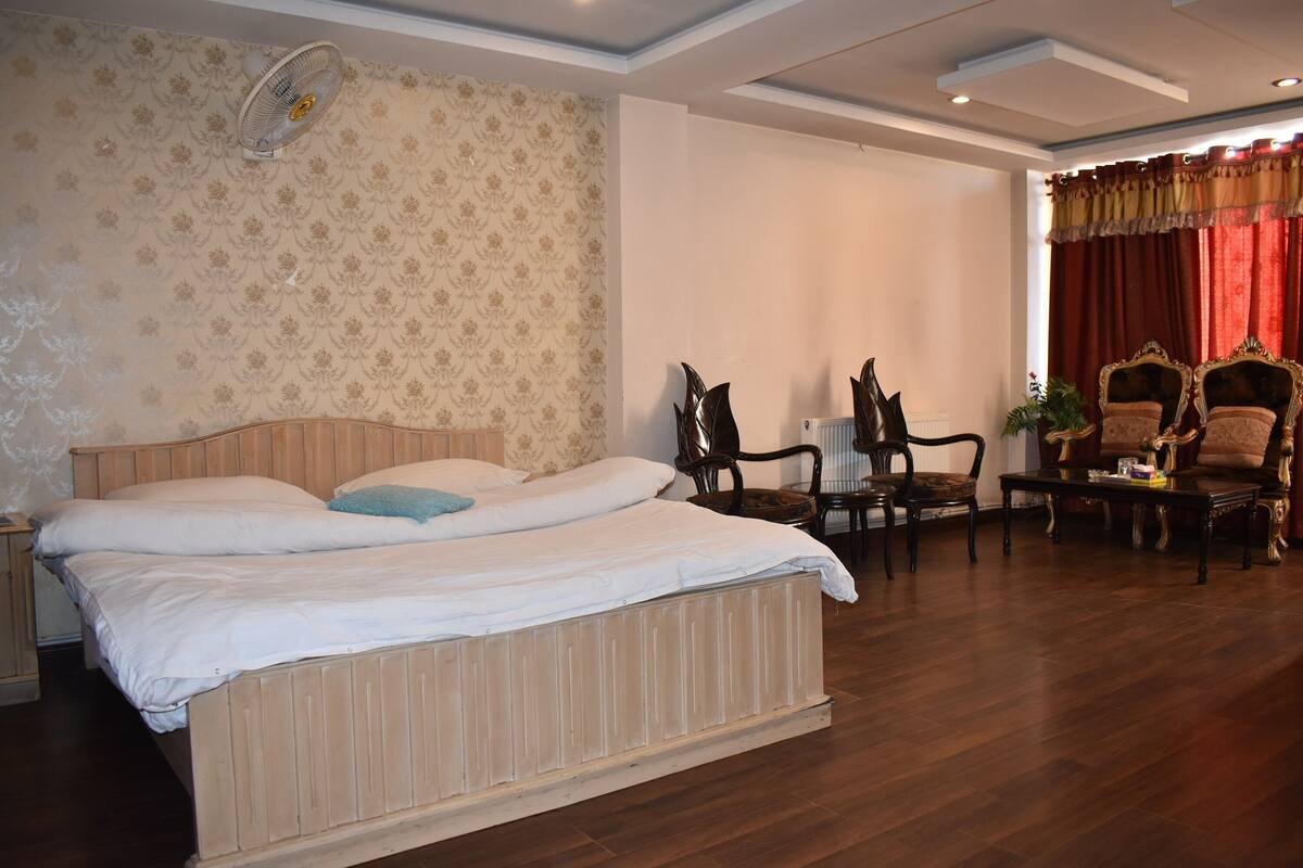 A bedroom with a large bed, two chairs, a small table, and a radiator.