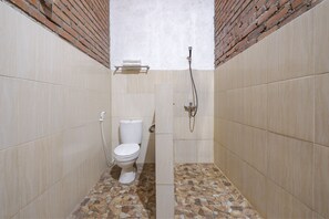 A small, tiled bathroom with a toilet, a shower, and a tiled floor. - OYO 2380 Alea Guesthouse (Borobudur)