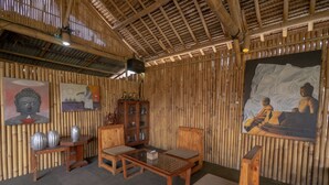 Une pièce aux murs en bambou, aux meubles en bois et aux tableaux religieux.