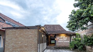 Un bâtiment en briques sur lequel on peut lire l’inscription suivante : « ALEA, CAFÉ, GALERIE D’ART, MAISON D’HÔTES ».
