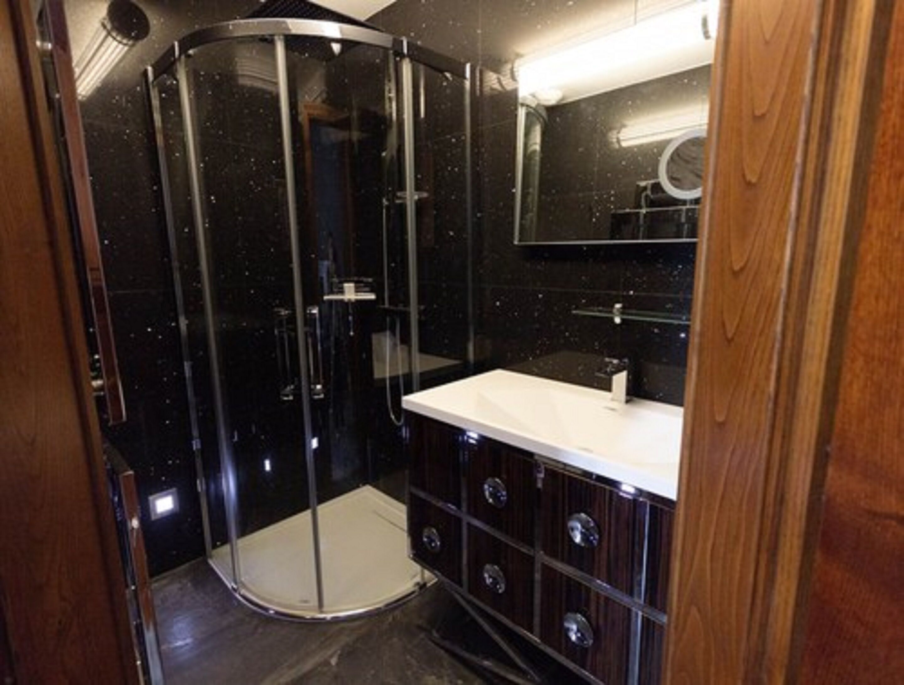 A modern bathroom with a glass-enclosed shower, a white sink, and wooden cabinetry.
