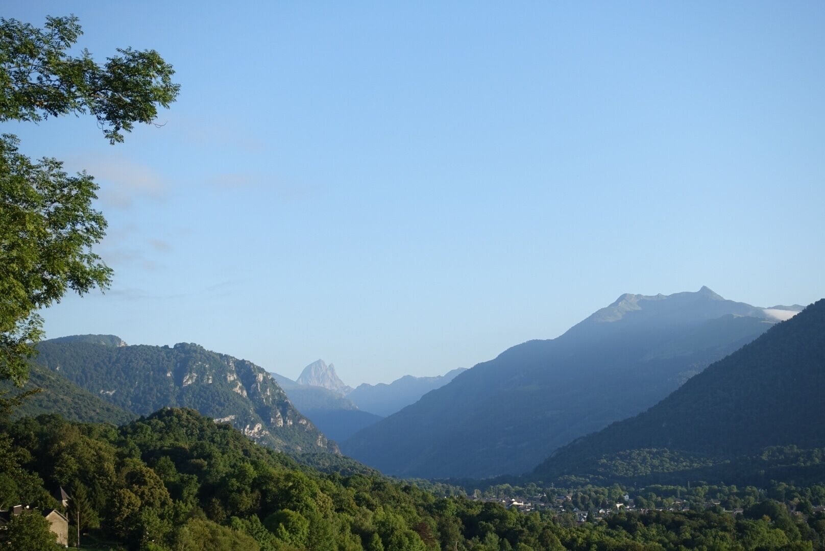 Paisagem montanhosa com florestas densas e um pequeno povoado.