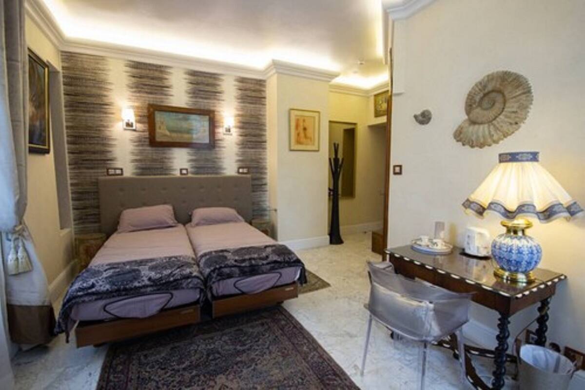 A double bed with a headboard, a bedside table with a lamp, and a chair.