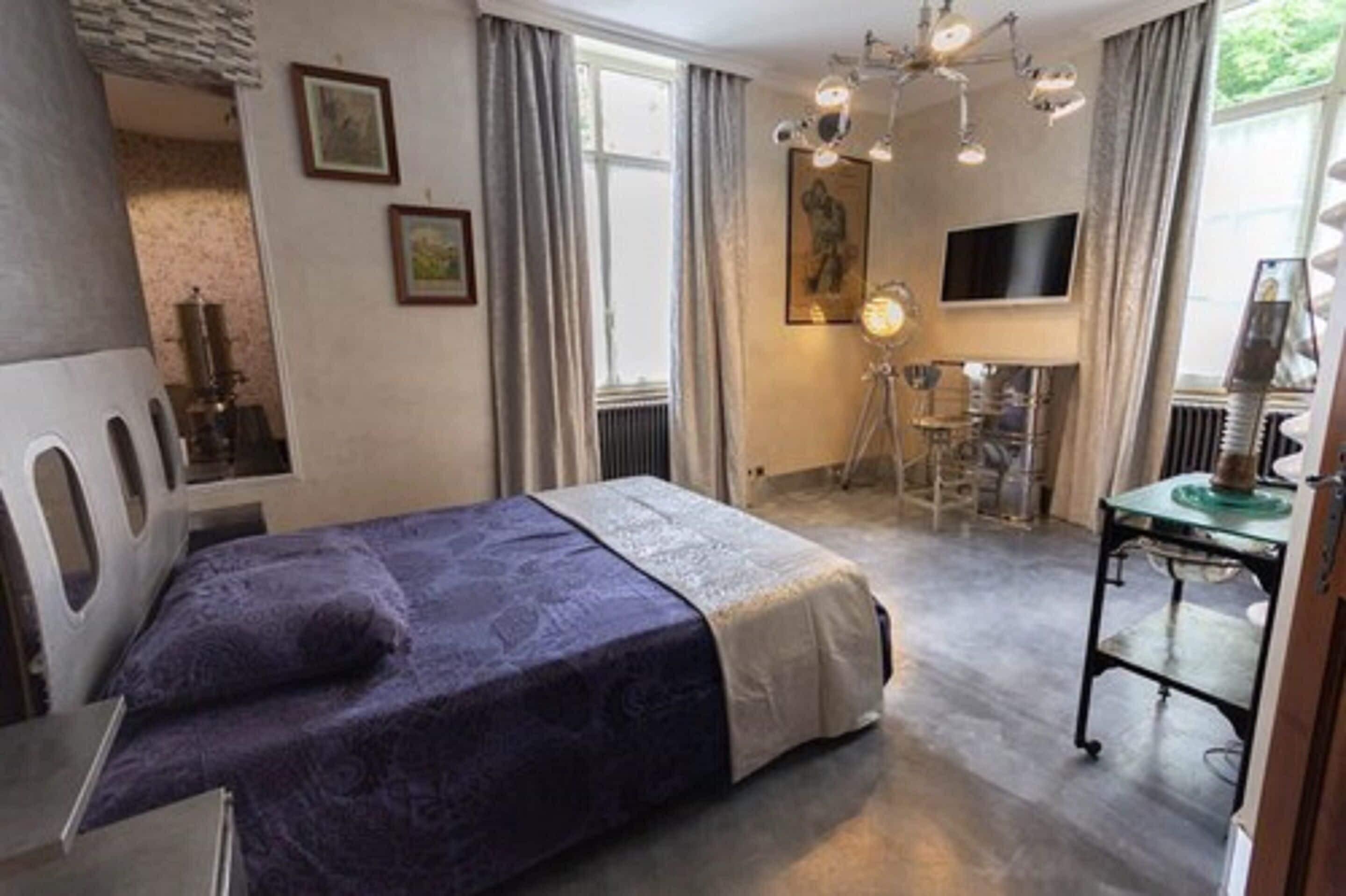 A bedroom with a bed, a desk, a chair, and a television.