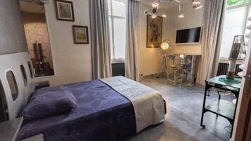 A bedroom with a bed, a desk, a chair, and a television.