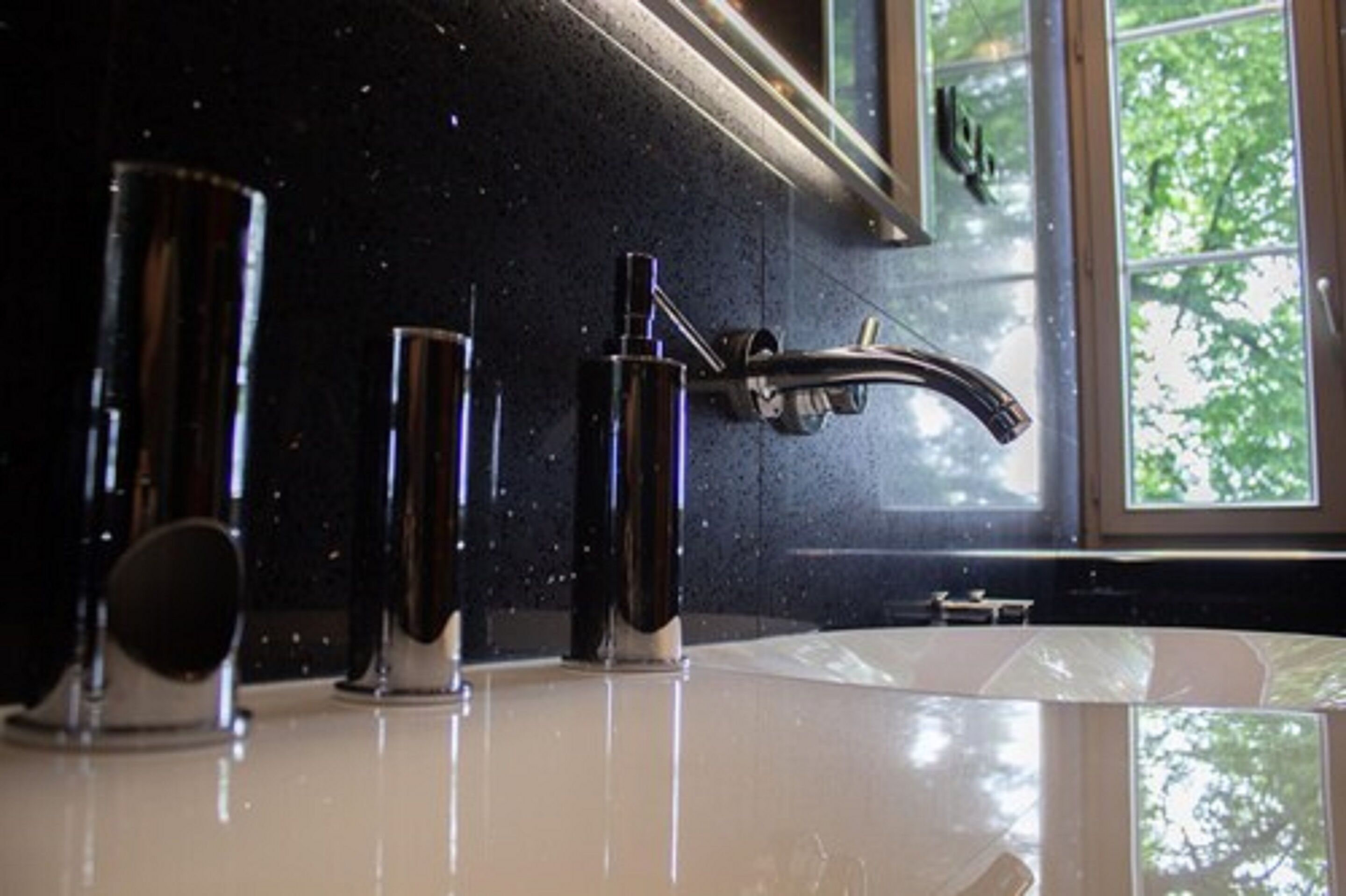 A bathroom with a modern sink, a mirror, and a window with a view of trees.