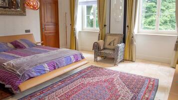 Un dormitorio con una cama grande, una silla, un escritorio y una ventana con cortinas.