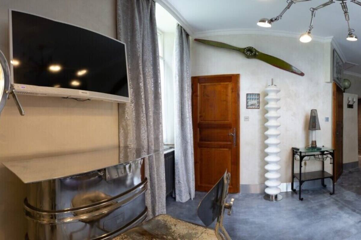 A bedroom with a bed, a mirror, a television, and a unique ceiling light fixture.