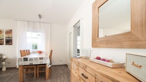 Une pièce moderne avec une table à manger en bois, des murs blancs et un grand miroir.