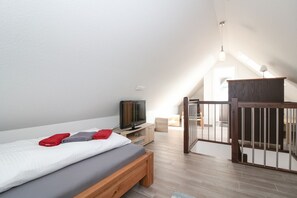 Un dormitorio moderno con cama, televisor y un banco de madera.