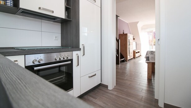 Une cuisine moderne avec des armoires blanches, un four encastré et un plan de travail en bois.