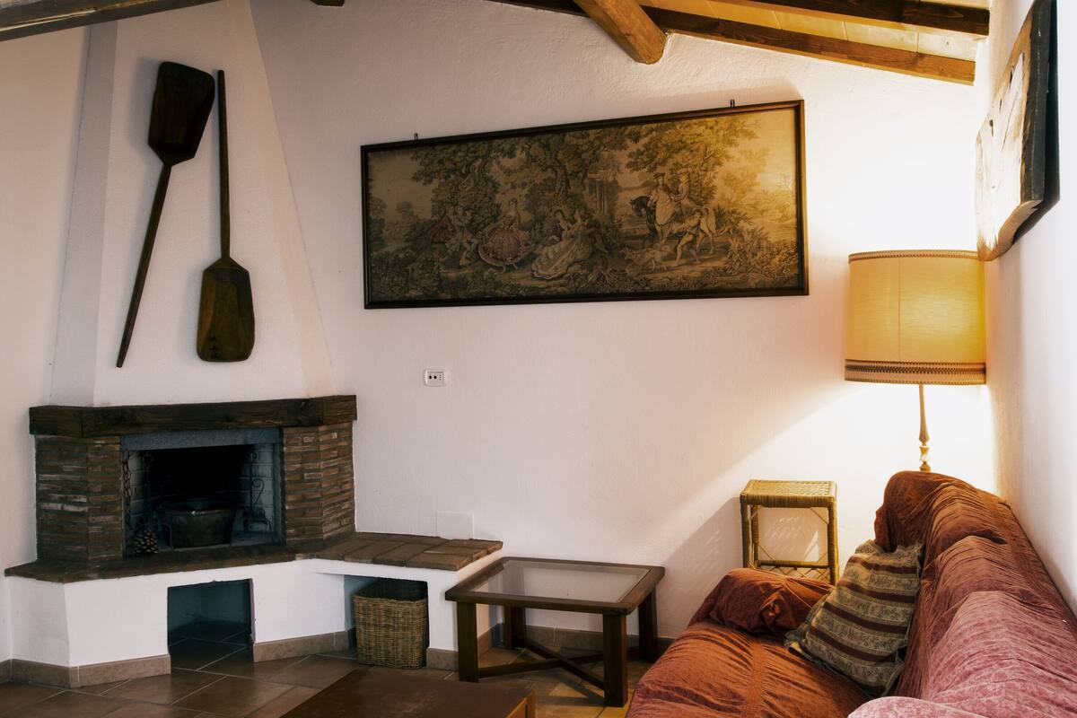A cozy living room with a fireplace, a sofa, a table, and a lamp.