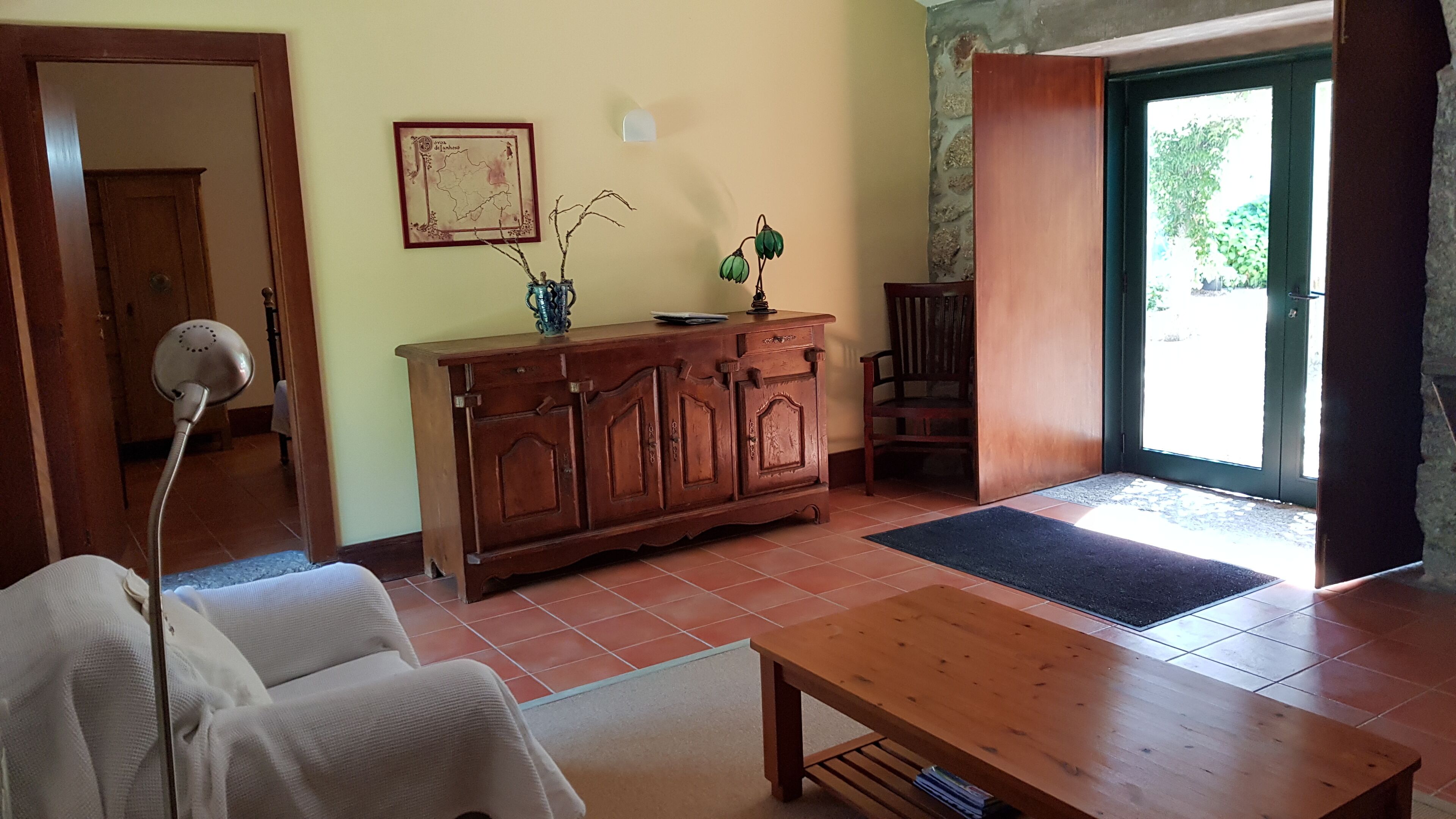 A living room with a wooden cabinet, a sofa, a coffee table, and a door leading outside.