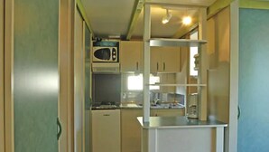 Een kleine keuken met een magnetron, spoelbak en een koelkast.