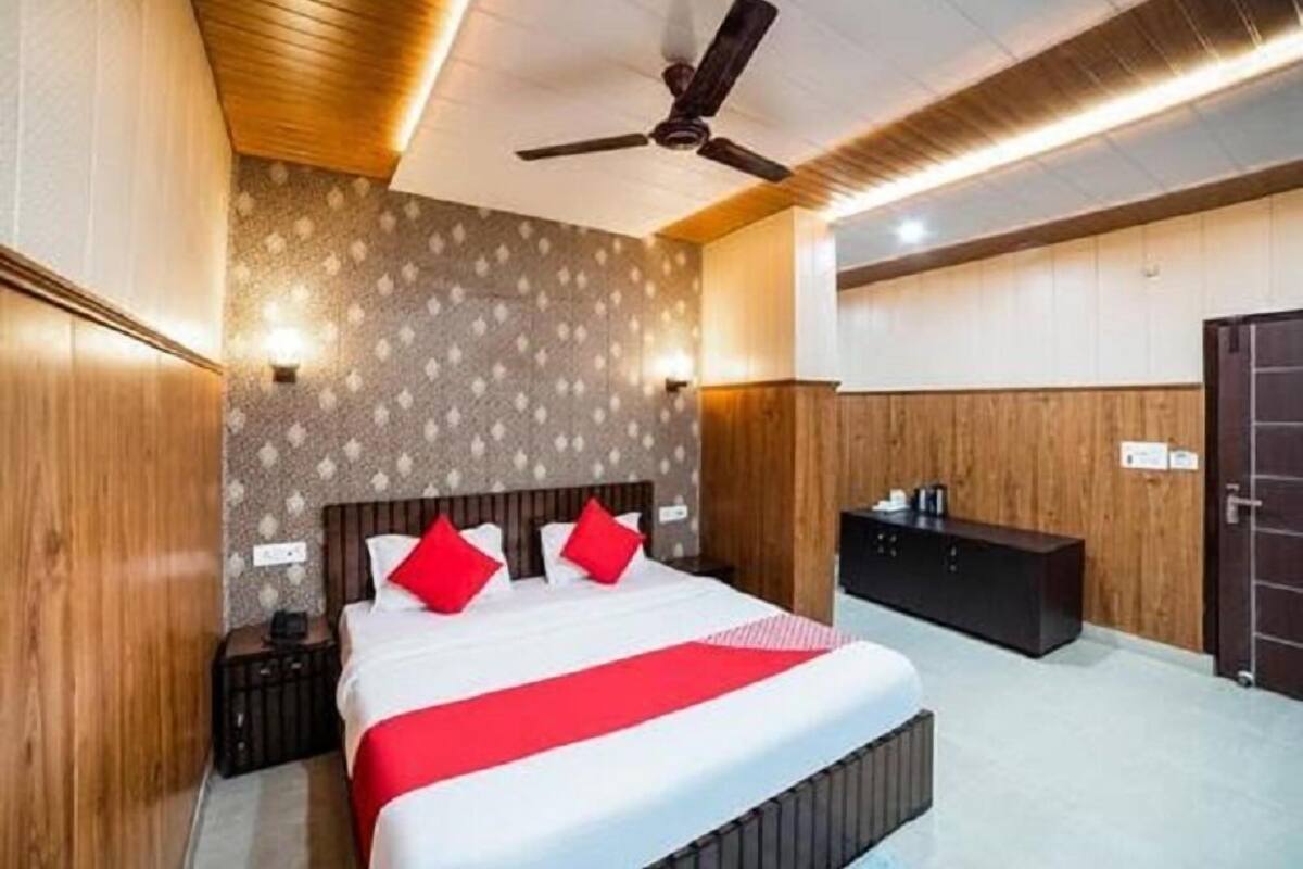 A hotel room with a bed, a ceiling fan, a nightstand, and a dresser.