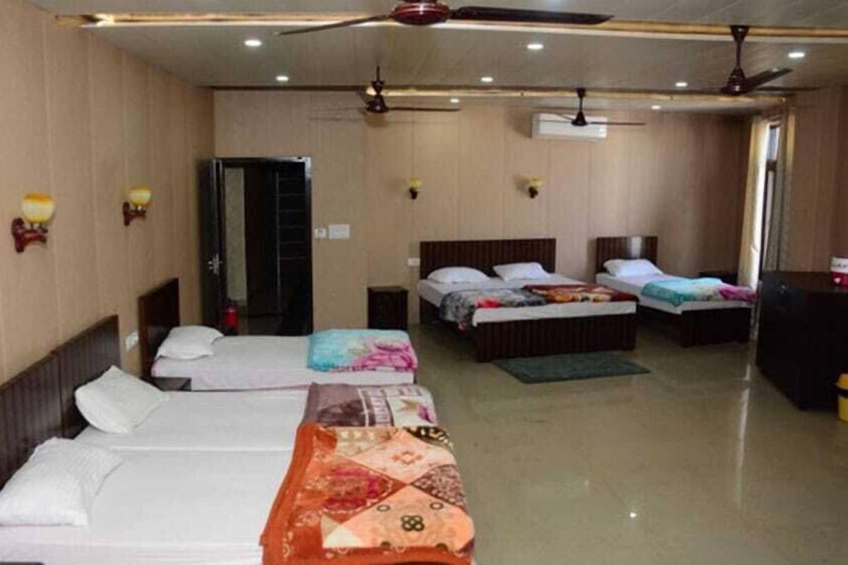 A hotel room with three single beds, a wardrobe, a ceiling fan, and a large window.
