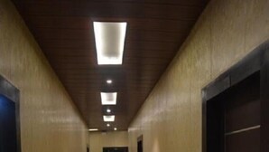 A hallway with a black stripe on the floor, beige walls, and a wooden ceiling. - Krazy Hotel (Haldwani)