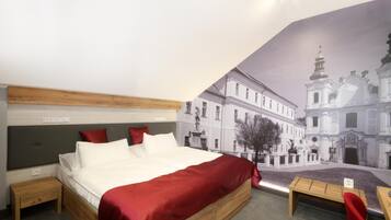 Una habitación de hotel con una cama, mesitas de noche, una silla roja y un mural de un edificio.