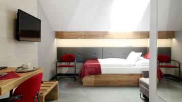 A modern hotel room with a loft bed, a desk with a chair, a television, and a large mirror.