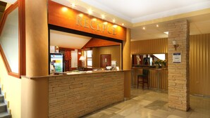 A reception area with a stone counter, a reception desk, and a staircase leading to an upper floor. - Hotel Strážnice (Straznice)