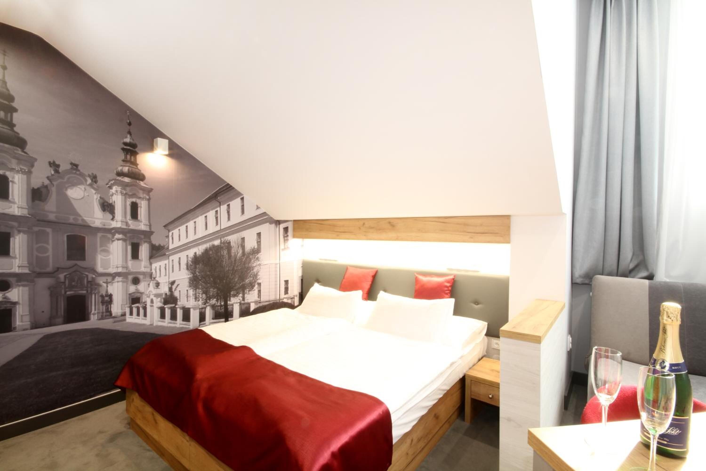 Una habitación de hotel con una cama, una mesita de noche, una botella de champán y una copa sobre la mesita.