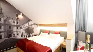 Una habitación de hotel con una cama, una mesita de noche, una botella de champán y una copa sobre la mesita.