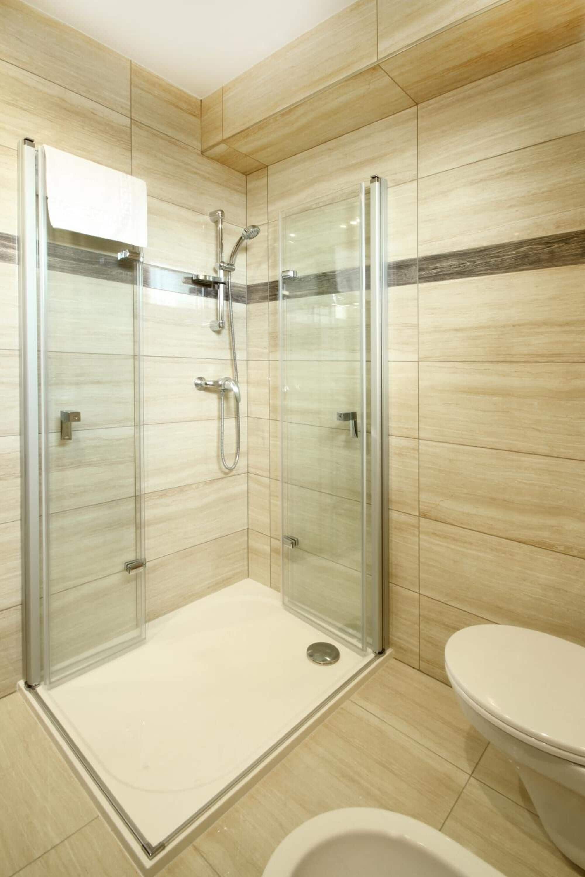 A modern bathroom with a glass-enclosed shower, a toilet, and a sink.