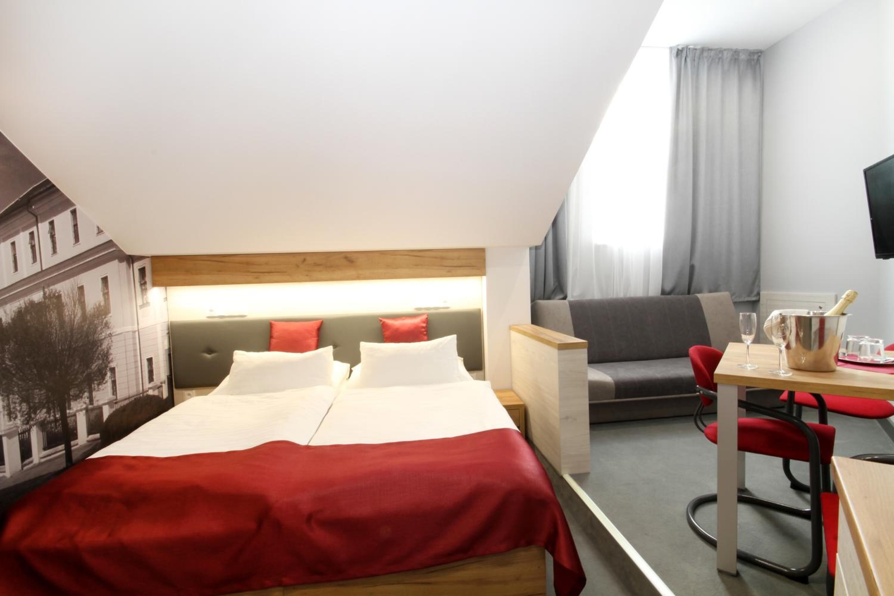 Ein Hotelzimmer mit einem Bett, einer Couch, einem Schreibtisch und einem Fernseher.