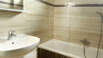 A bathroom with a sink, mirror, and bathtub.