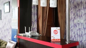A reception desk with a red top, a white sign, and a telephone. - OYO 2343 Winolanto Guest House Syariah (Balikpapan)