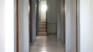 A narrow, tiled hallway with wooden trim and a staircase leading to a bright room. - OYO 2343 Winolanto Guest House Syariah (Balikpapan)