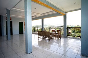 A spacious indoor area with tiled flooring, a balcony with a railing, and a seating arrangement. - OYO 2343 Winolanto Guest House Syariah (Balikpapan)