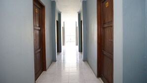 A hallway with wooden doors and light blue walls. - OYO 2343 Winolanto Guest House Syariah (Balikpapan)